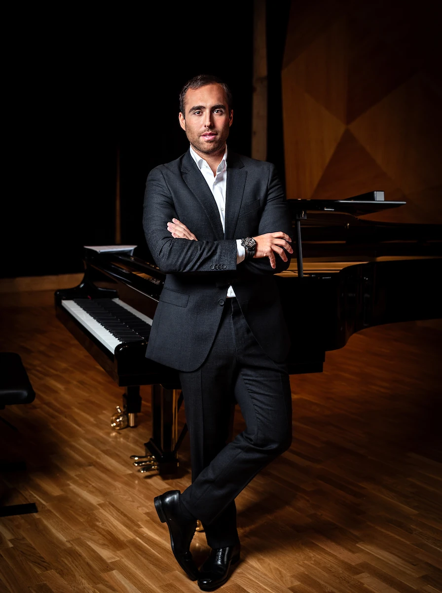 Alfonso G. Aguilar de pie junto a un piano de cola